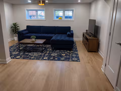 Living room with a blue sofa, rug and TV